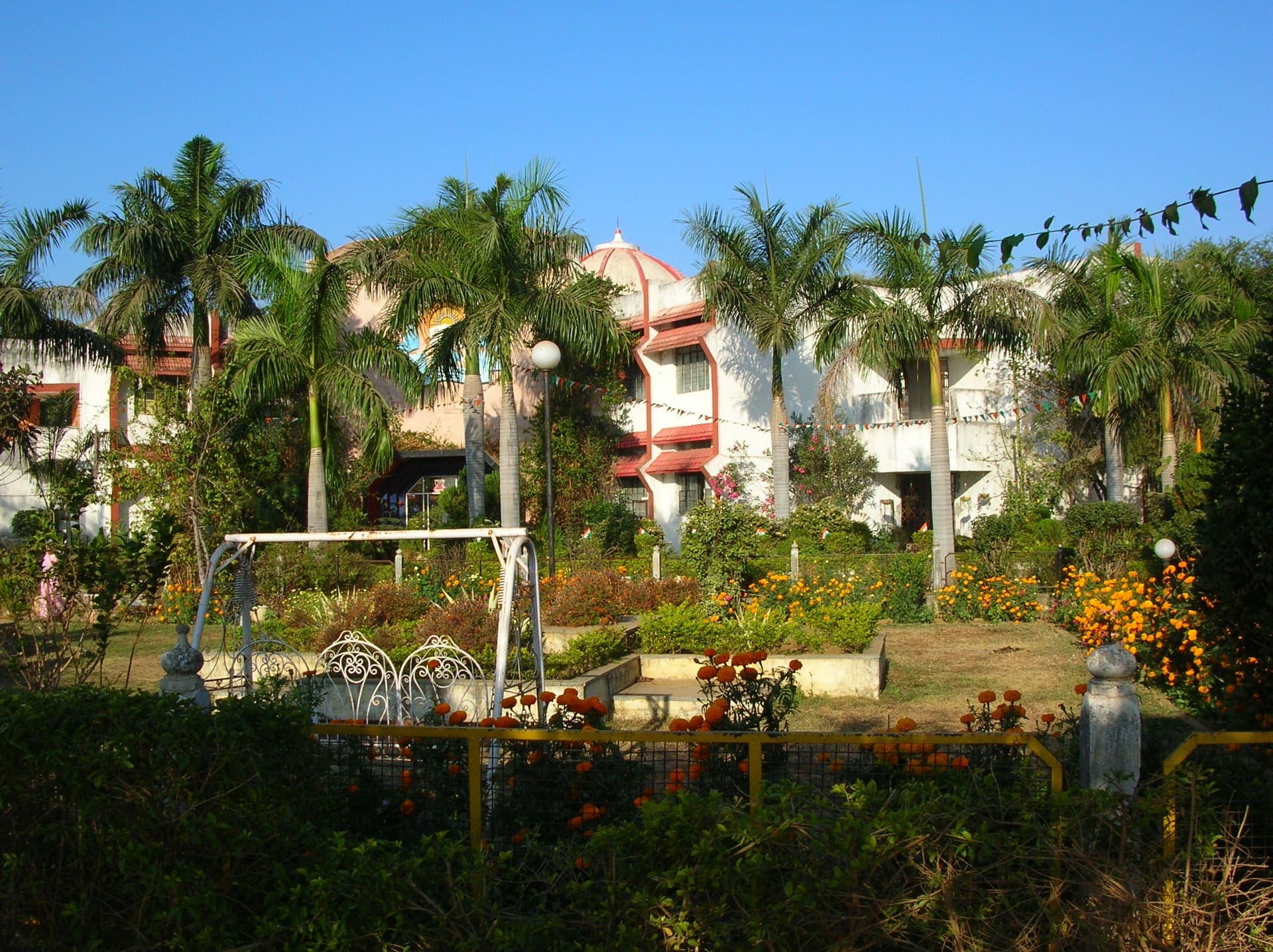 The main academic block at Radiant Public School, framed by palms and a marigold garden